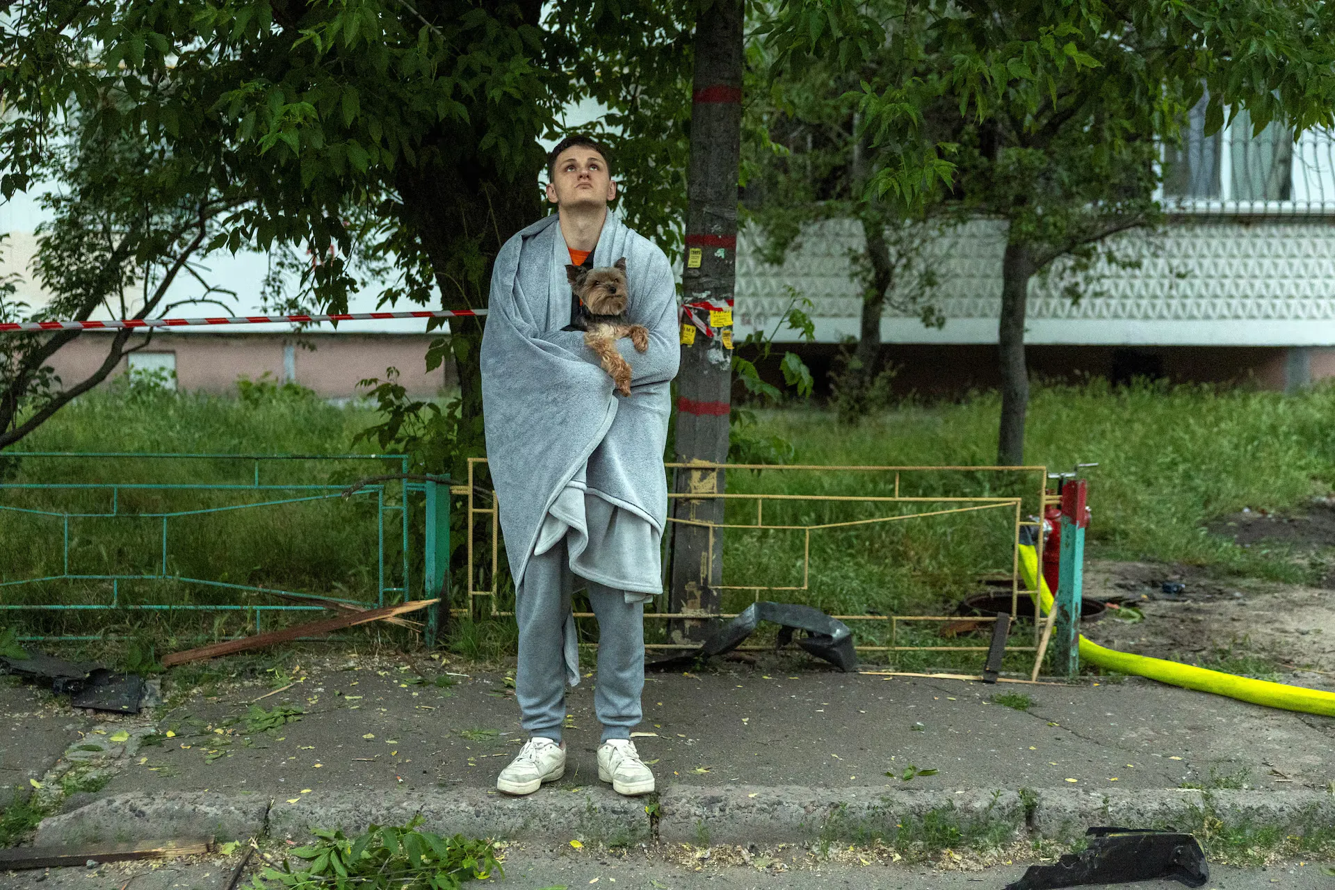 Мешканець тримає своїх собак, оглядаючи багатоквартирний будинок, пошкоджений під час удару російського безпілотника на тлі нападу Росії на Україну, у Києві, Україна, 24 травня 2025 року.